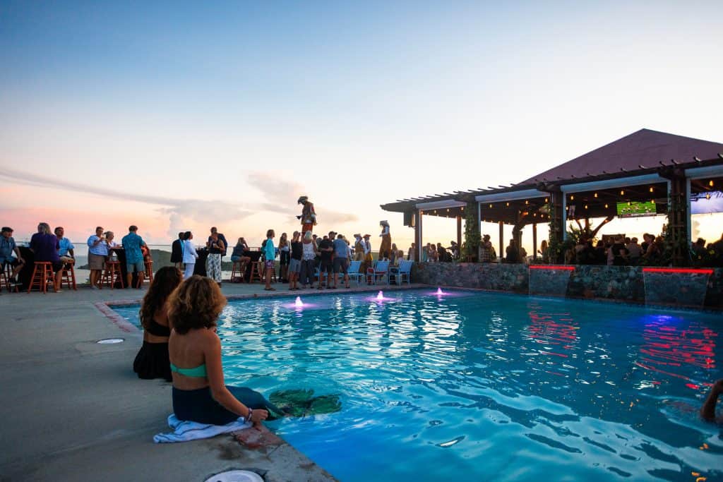 People enjoying a sunset poolside event at Blackbeard's Castle, with scenic views and social atmosph.