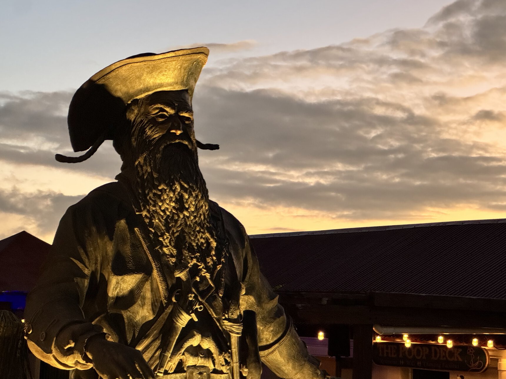 Blackbeard statue glowing at sunset beside the pirate bar at Jolly Roger's in St. Thomas