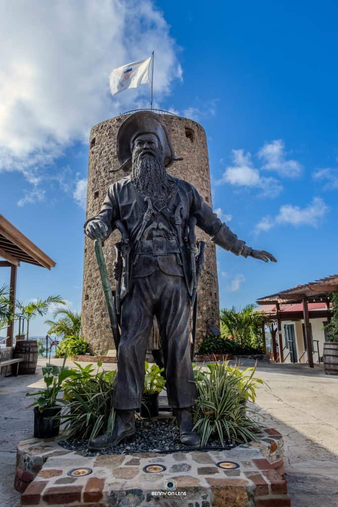 Pirate statue at Blackbeard's Castle with historic tower and blue sky background.