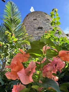 Historic stone tower at Blackbeard's Castle with lush greenery and flowers.