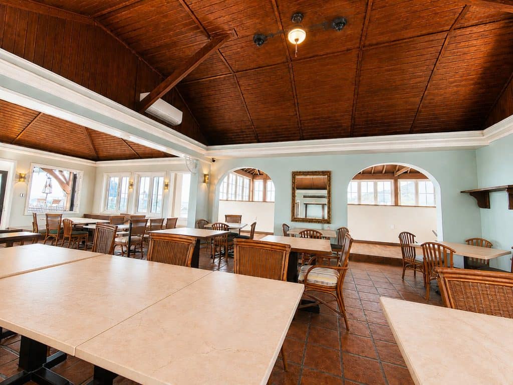 Interior of a historic dining room with wooden ceiling and large windows.